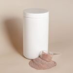Frasco blanco sin marca con polvo y cuchara medidora sobre fondo neutro