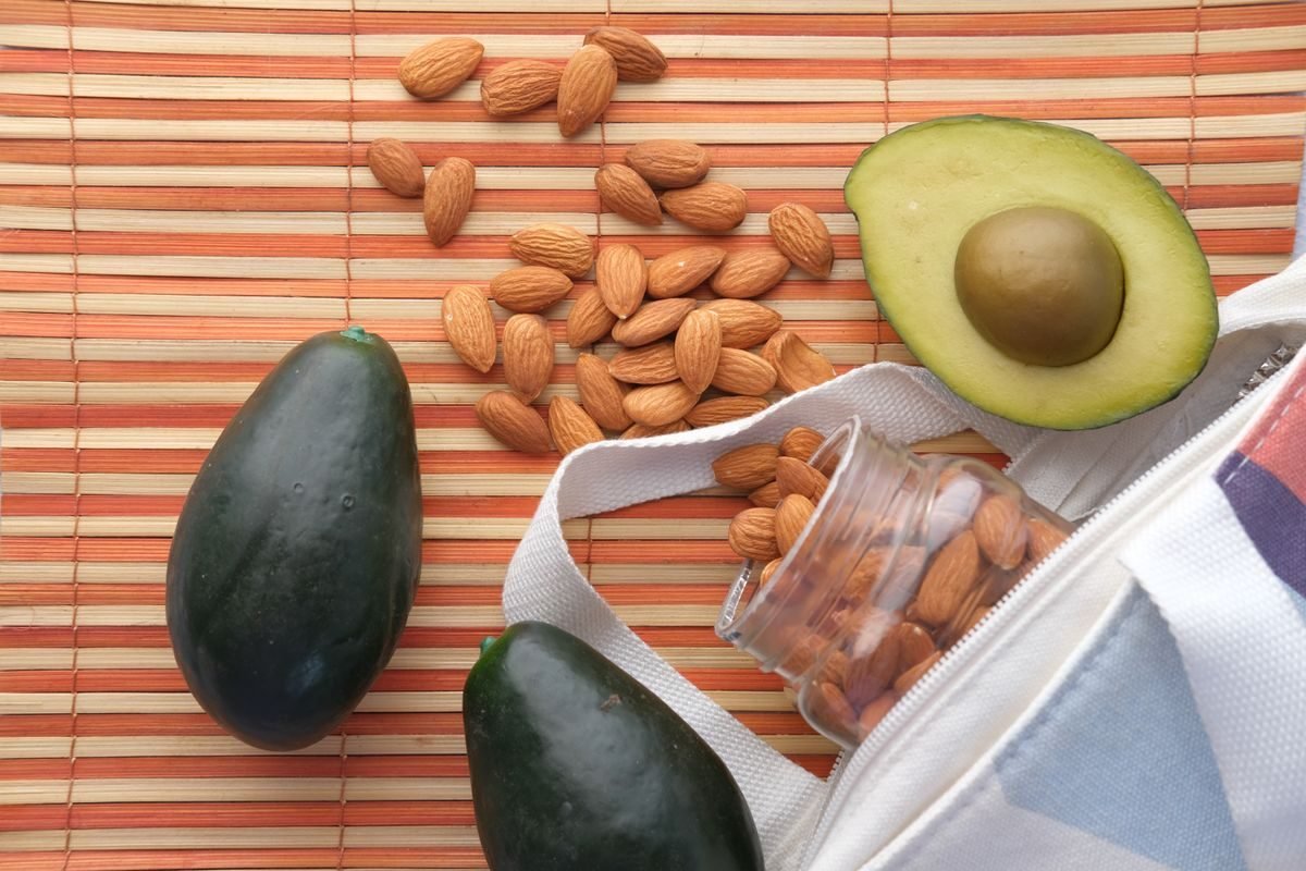 Aguacates y almendras sobre un mantel de bambú
